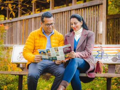 A Sikh family sitting on a bench looking at a brochure.